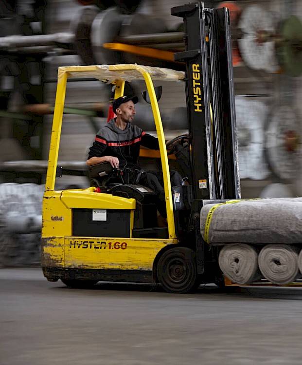 warehouseman driving forklift to transport fabrics